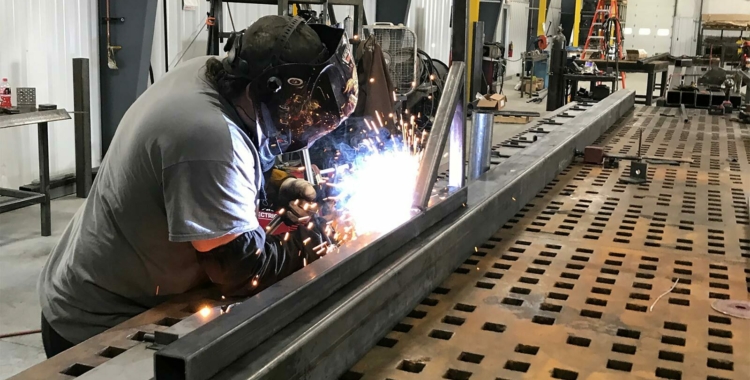 A BoxPop employee welding a custom shipping container